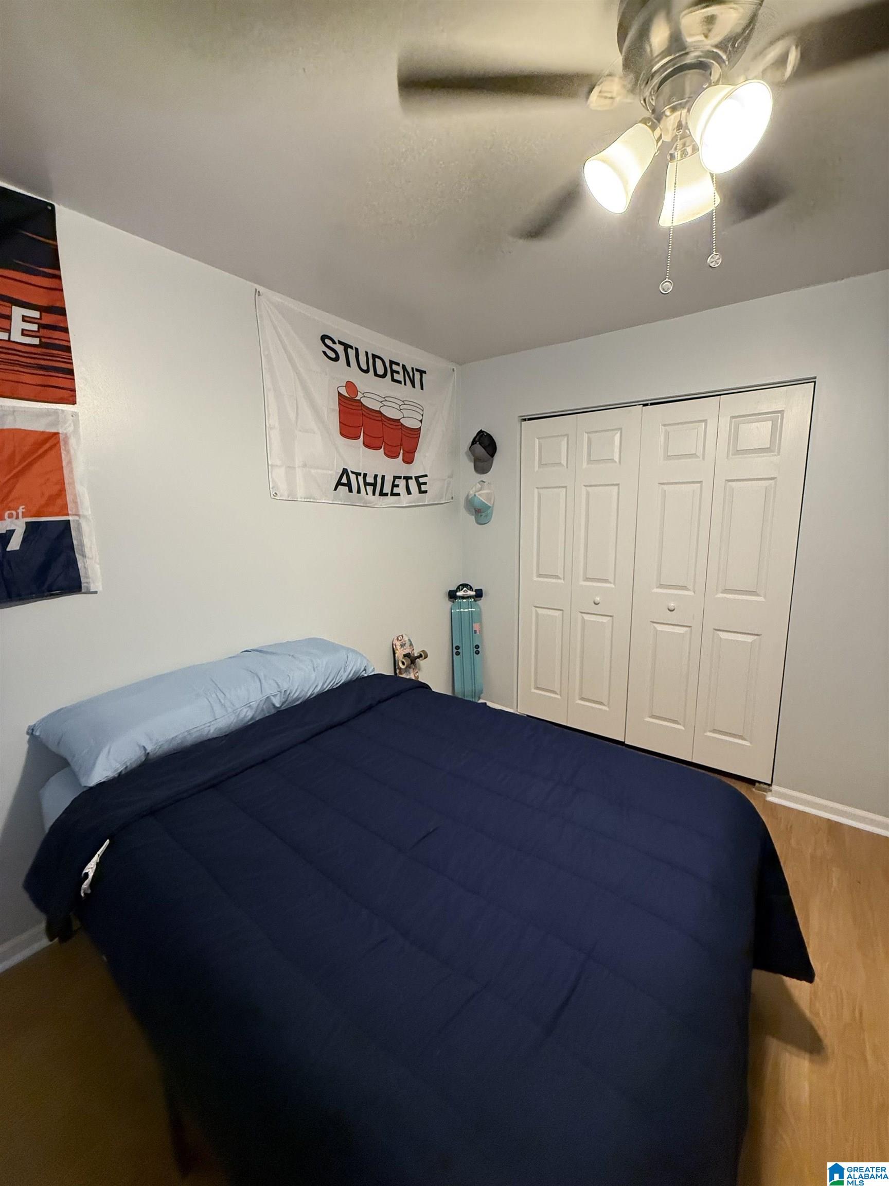 Bedroom with navy bedding, white closet doors, and student-athlete sports decor.