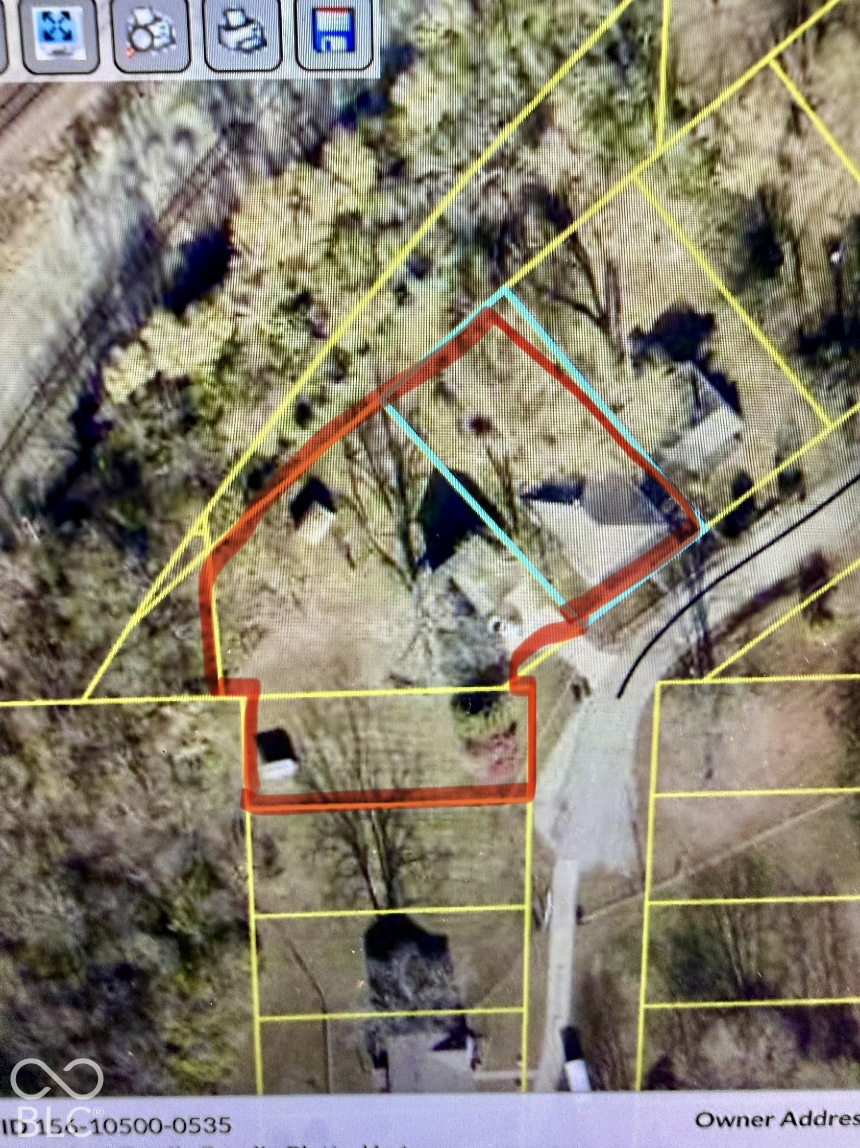 Aerial view of a tree-lined property and house, with the lot outlined in red and cyan.