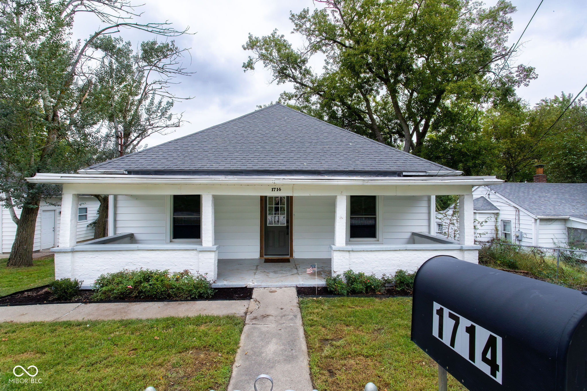 White single-story house with a broad columned porch and a large mailbox marked 1714.