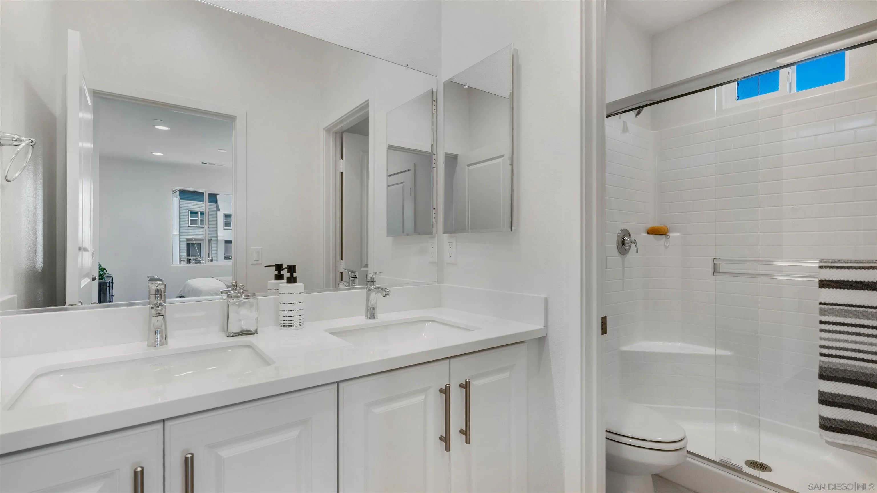 Bathroom with a double-sink vanity and glass-enclosed tub and shower.