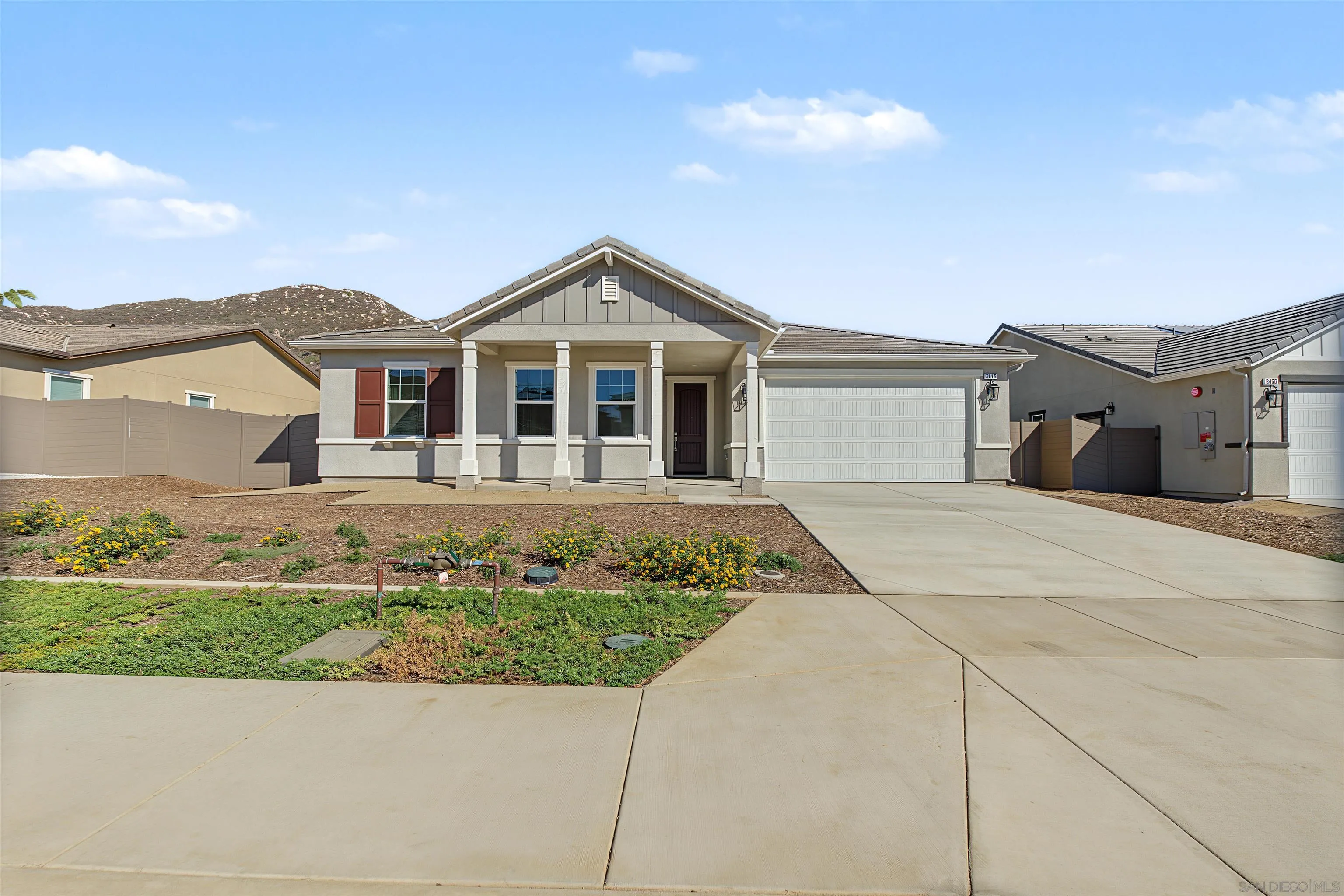 Single-story gray home with a covered entry, two-car garage, and landscaped front yard.