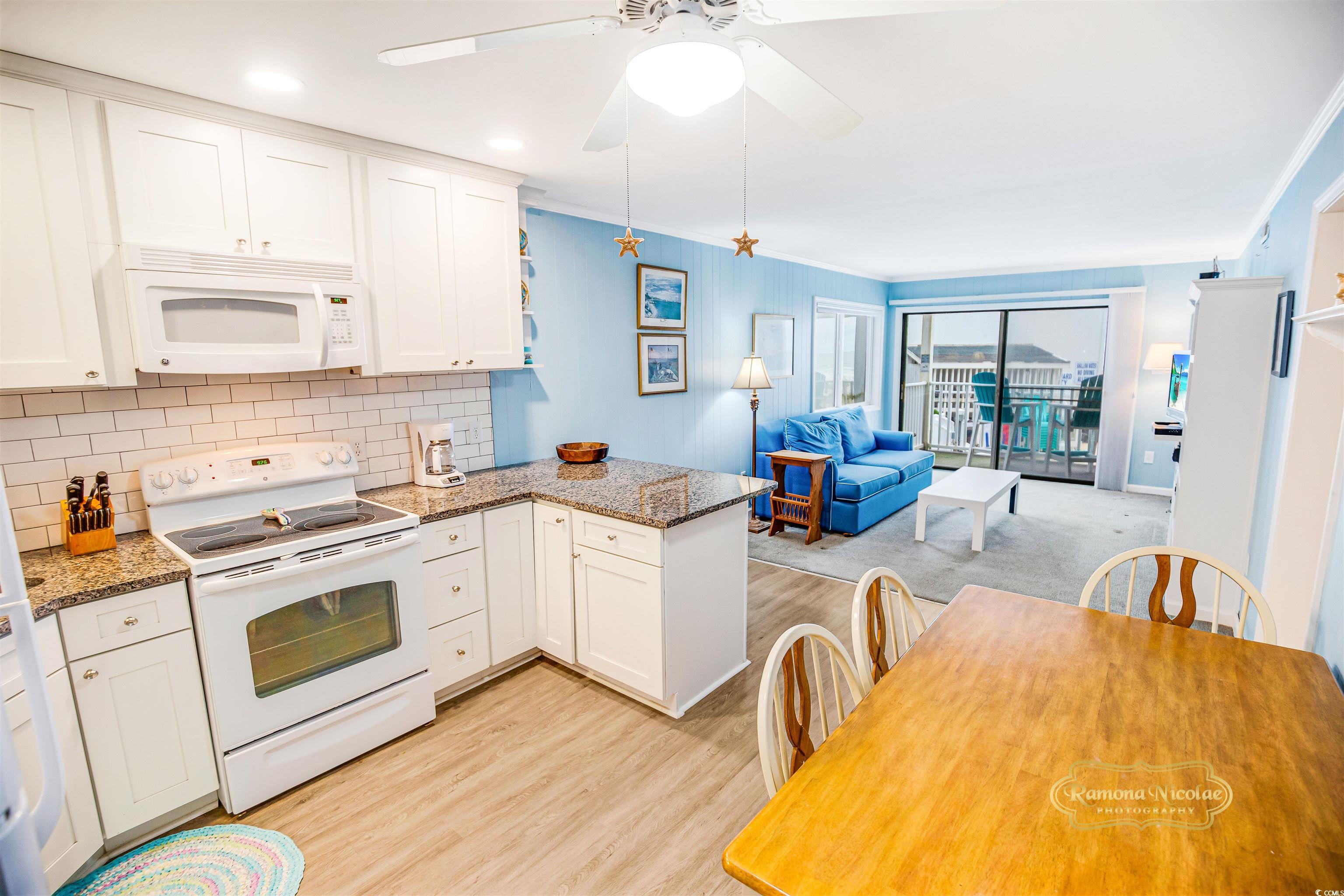 Open-plan condo kitchen and living room with blue sofa and balcony overlooking the ocean.