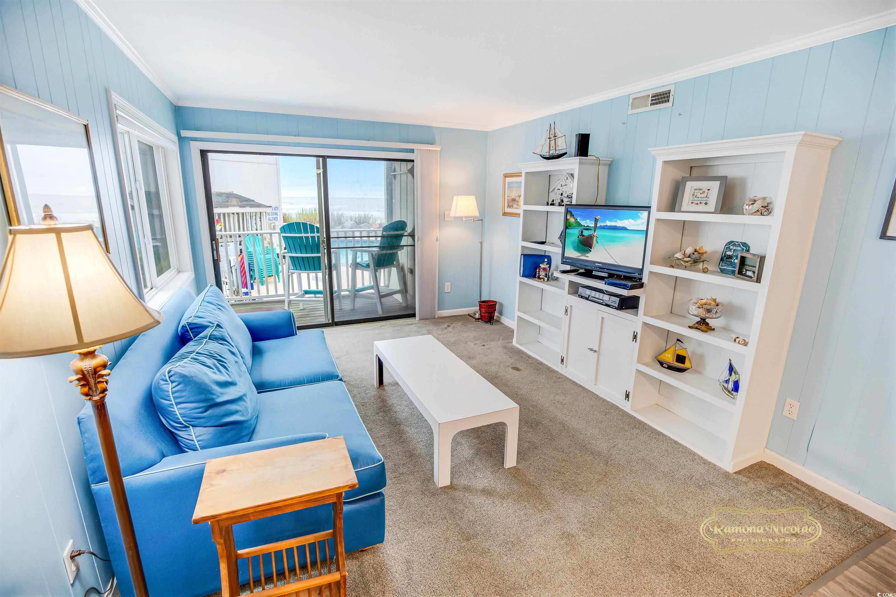 Living room with a blue sofa and sliding doors opening to a balcony with an ocean view.