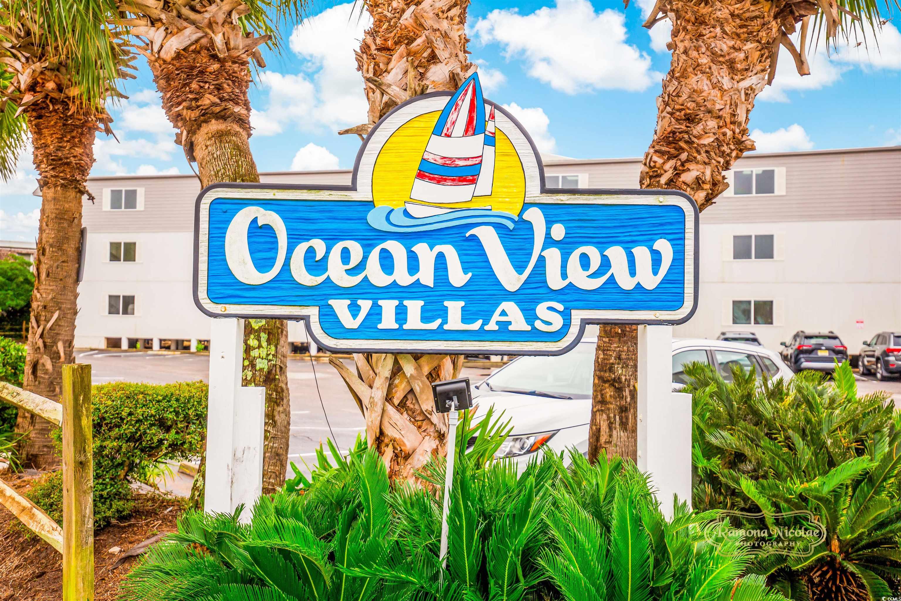 Ocean View Villas entrance sign in front of the condominium building, framed by palm trees.