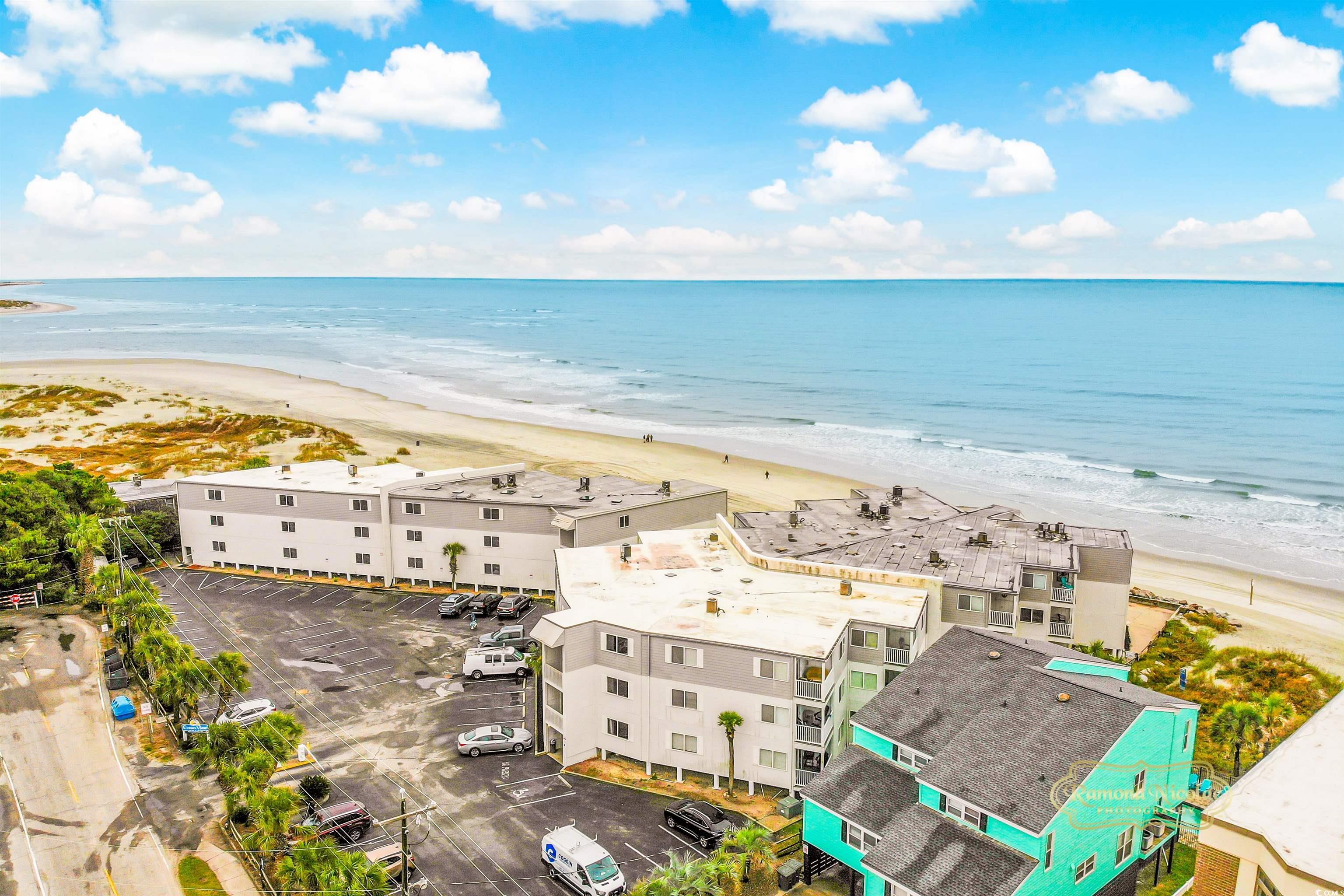 Beachfront condominium complex beside a wide sandy beach and ocean, viewed from above.