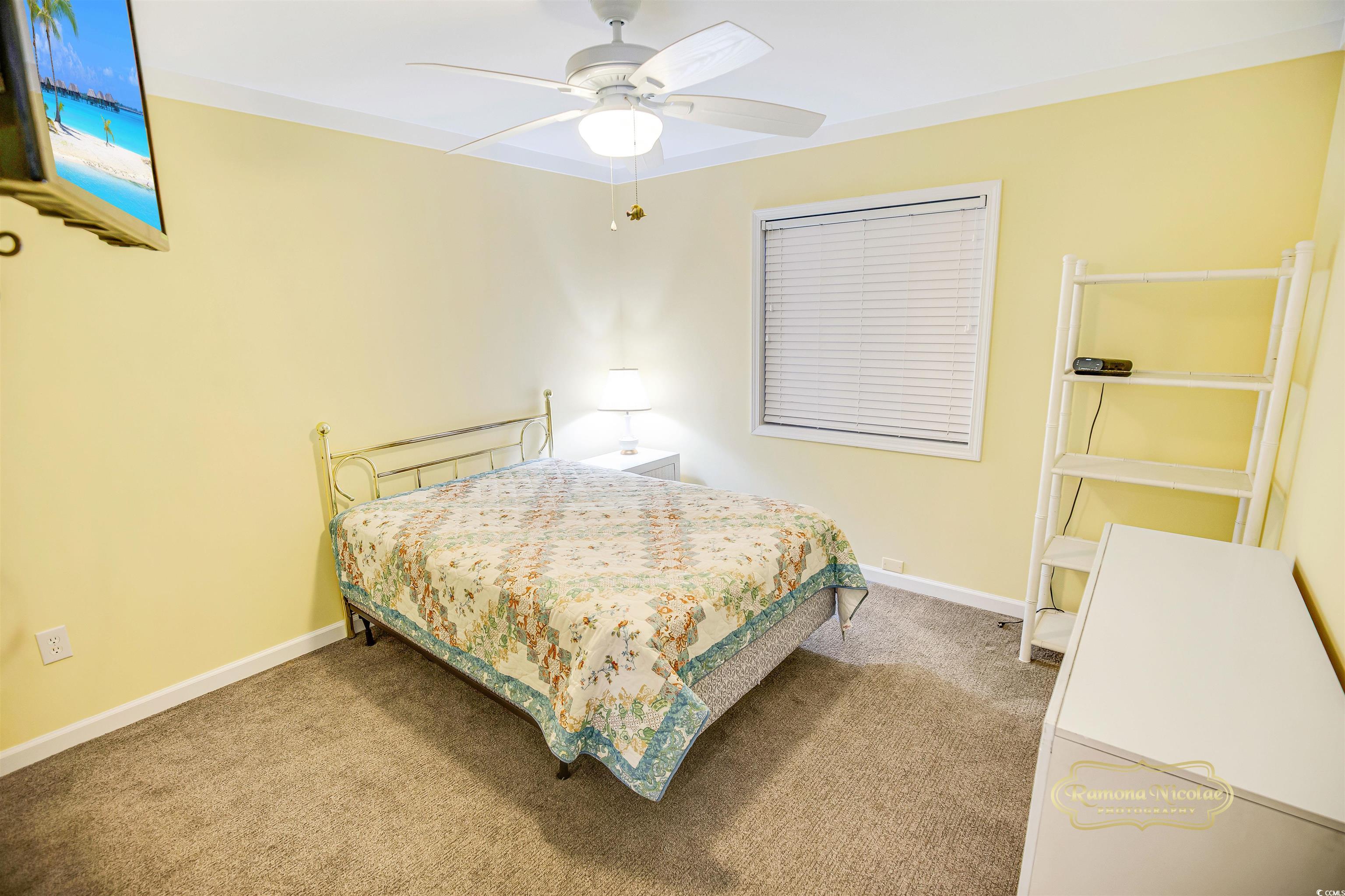 Bedroom with a brass bed, floral quilt, pale yellow walls, and white shelving.