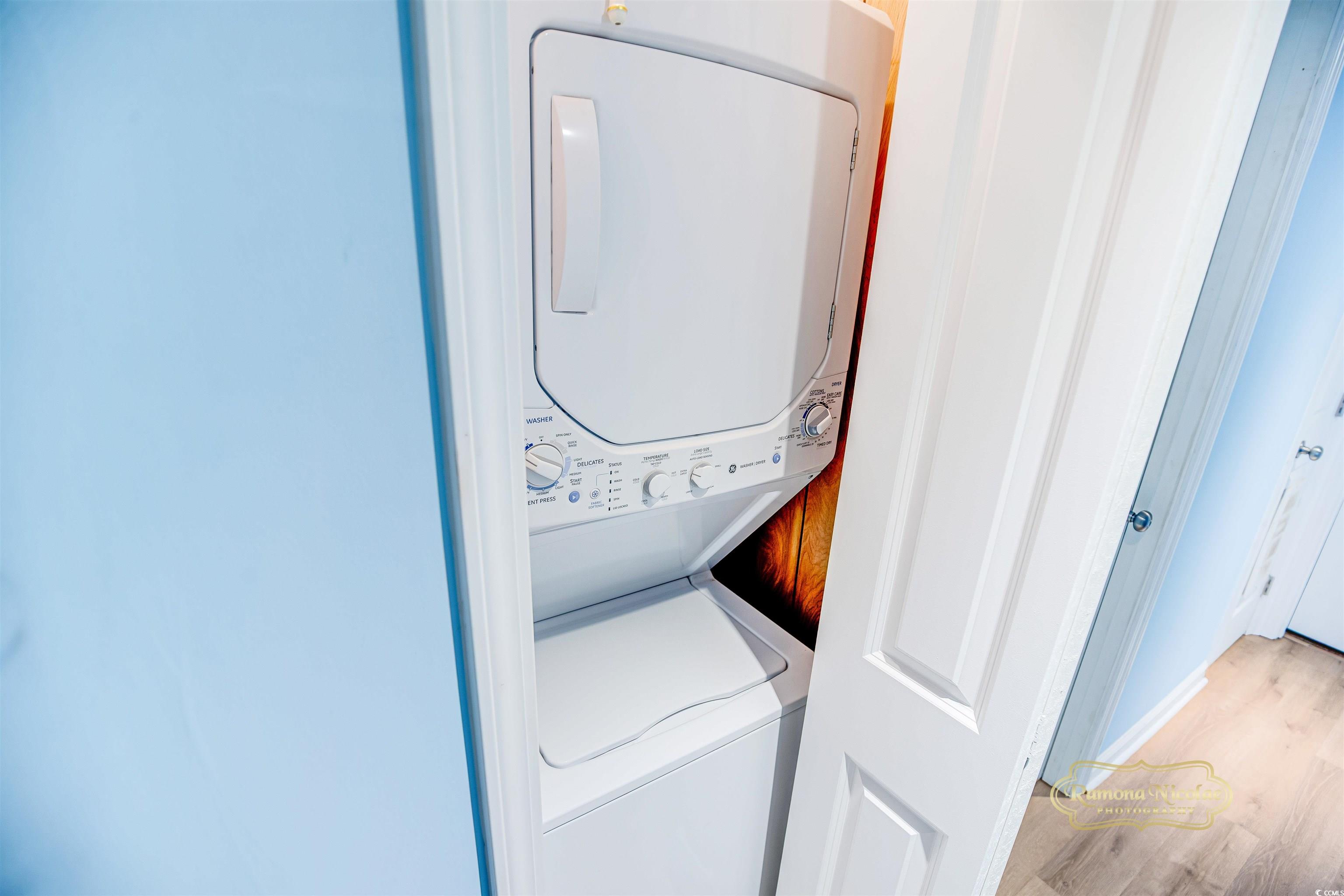 Stacked white washer and dryer inside a laundry closet with the door open.