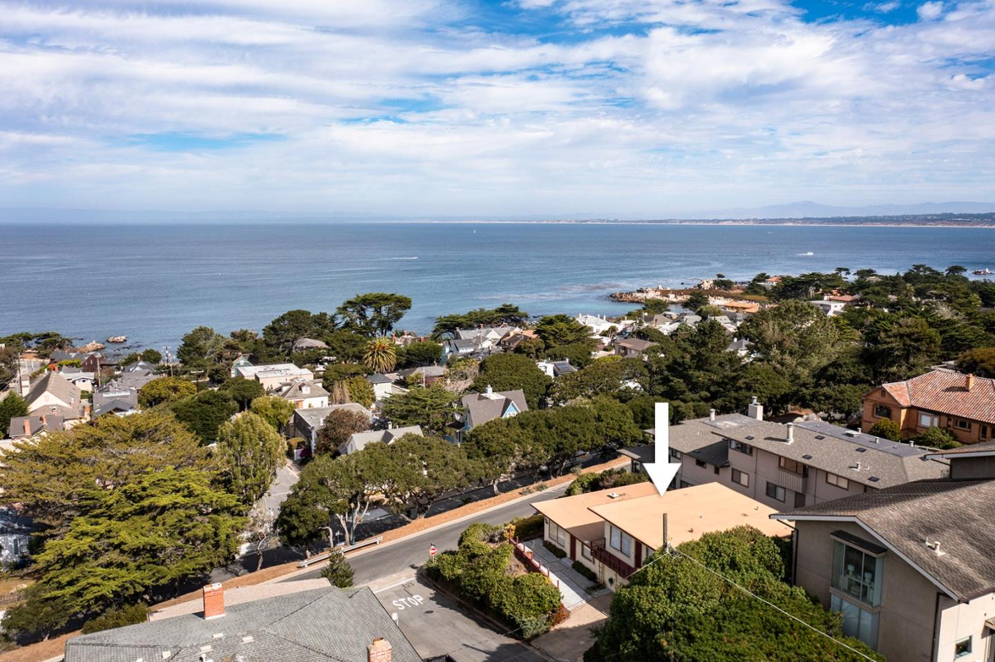 Coastal home marked by an arrow, with a panoramic view of the ocean and neighborhood.