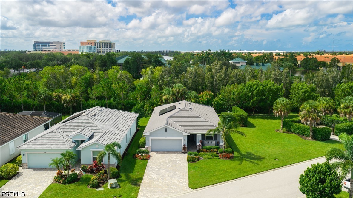 Aerial view of two single-story homes with tiled roofs, landscaped lawns, and wooded surroundings.