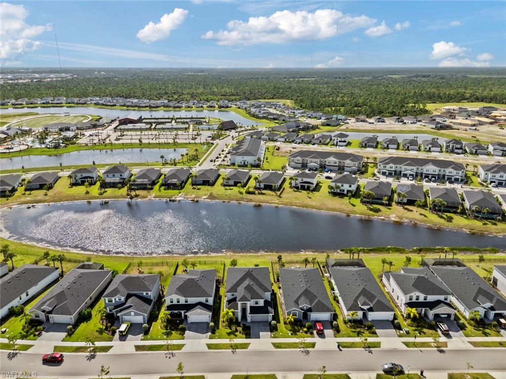 Aerial neighborhood view with homes lining a pond and a community recreation area.