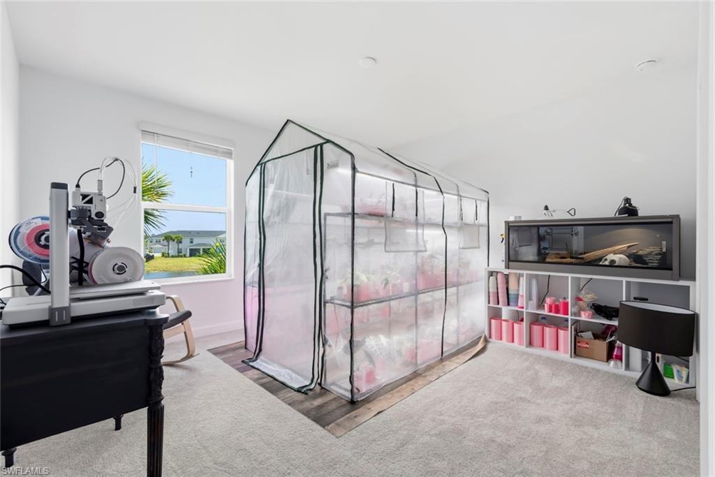 Bright workroom with a large transparent growing tent, sewing equipment, and shelves of craft supplies.