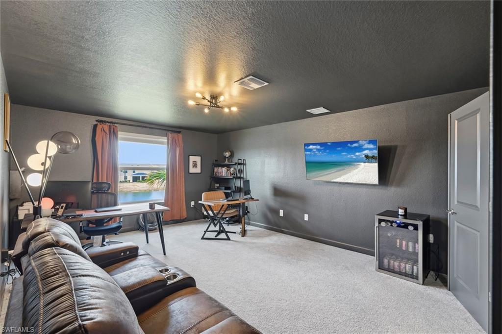 Furnished home office with a leather sectional, desk, and window overlooking water.