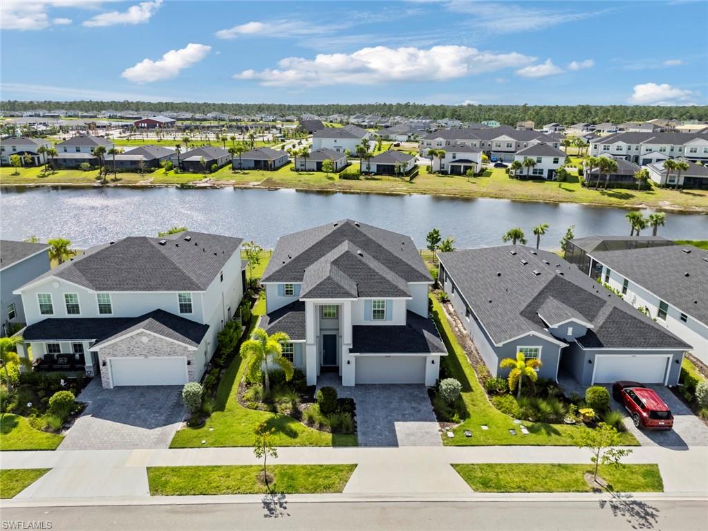 Aerial view of a two-story home beside a community lake, with neighboring houses.