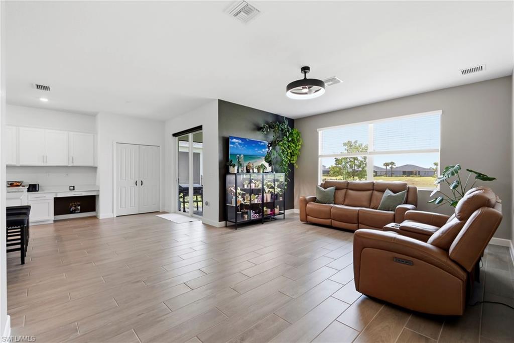 Open-plan living room with tan leather seating, a large window, and a glass display cabinet.
