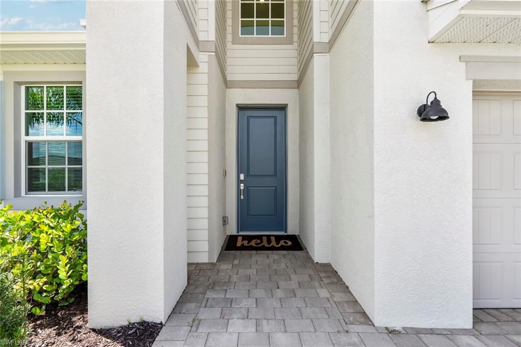 Home entrance with a recessed blue front door and gray paver walkway.