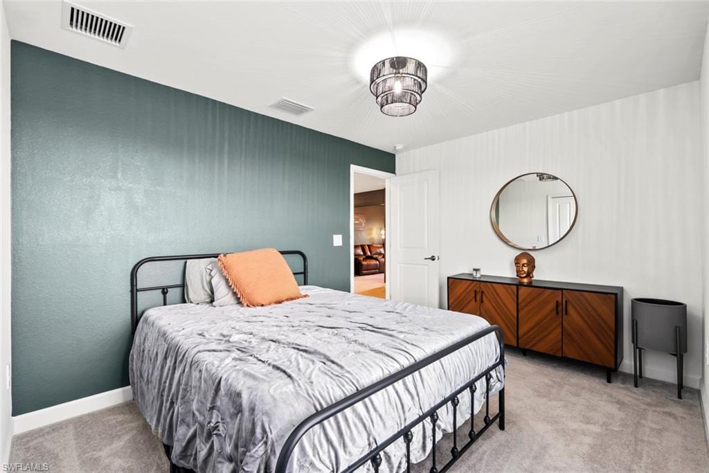 Bedroom with a black metal bed, teal accent wall, and mid-century wooden dresser.