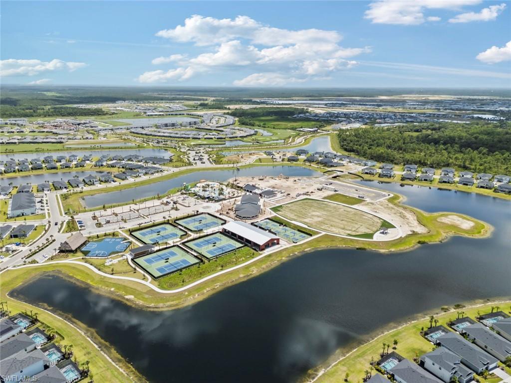 Aerial view of a waterfront community with tennis courts, lakes, and a recreation center.