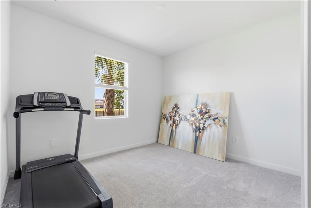 Exercise room with a treadmill, abstract painting, and window overlooking palm trees.