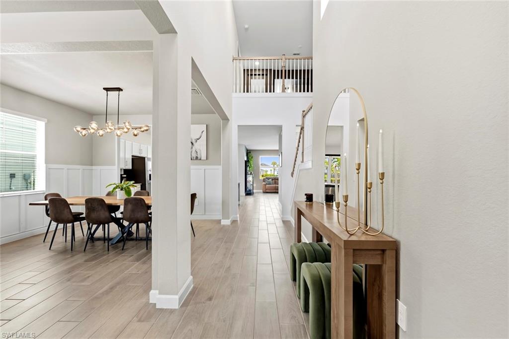 Two-story entry hall with an open staircase, console table, and dining area beneath a chandelier.