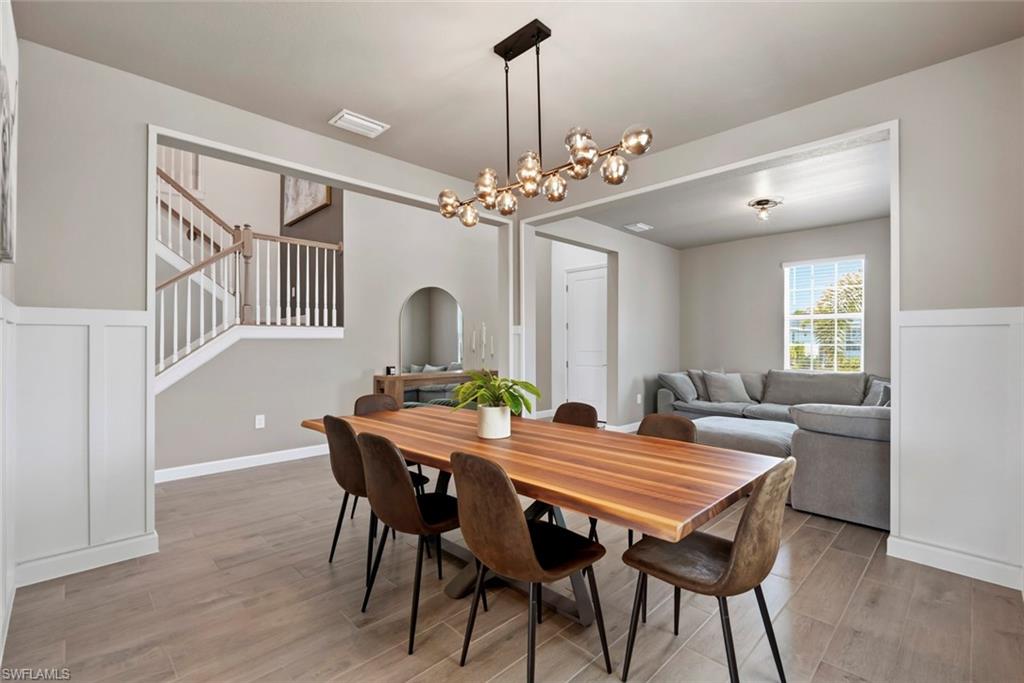 Dining room with a long wood table, globe chandelier, and view into the adjoining living room.