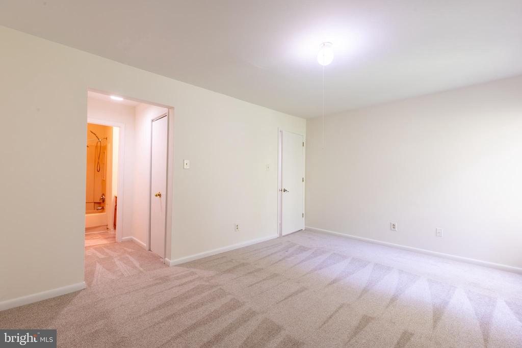 Empty carpeted bedroom with a doorway to an adjoining bathroom.