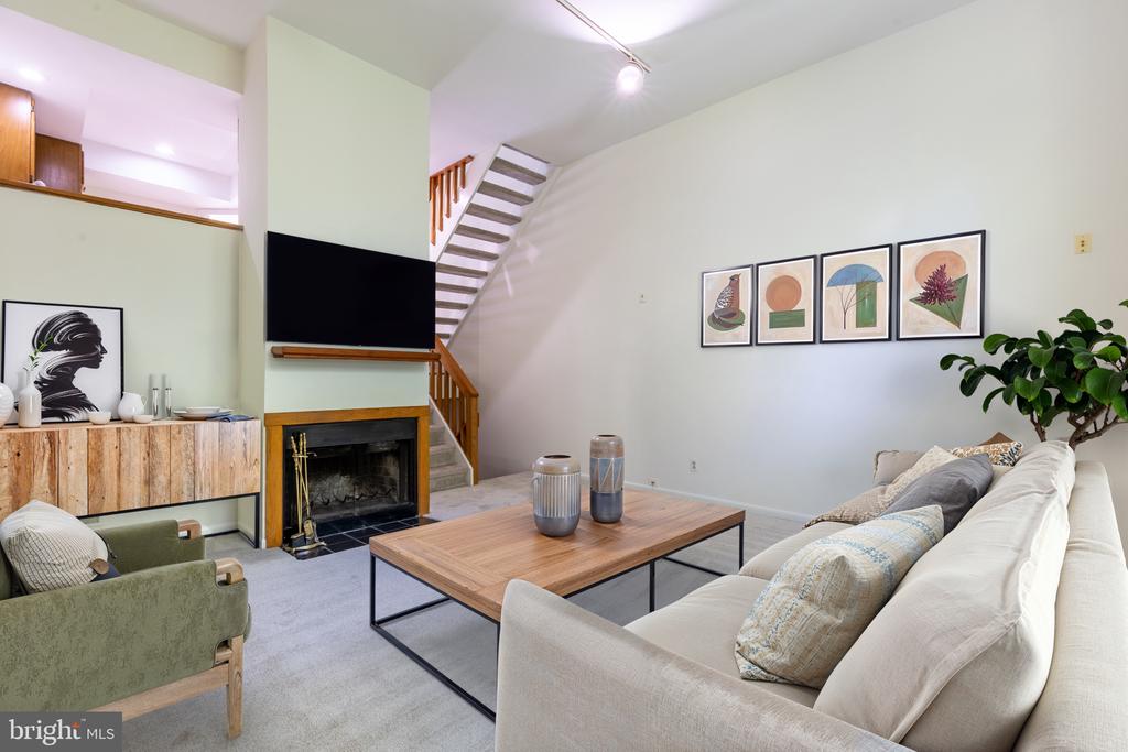 Living room with a white sectional, wood coffee table, fireplace, and open staircase.