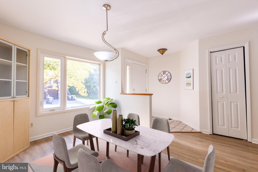 Dining room with a marble-look table, gray chairs, built-in cabinetry, and large windows overlooking greenery.