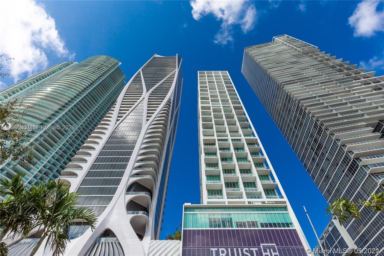 Modern high-rise buildings viewed from below, with curved balconies and blue sky.
