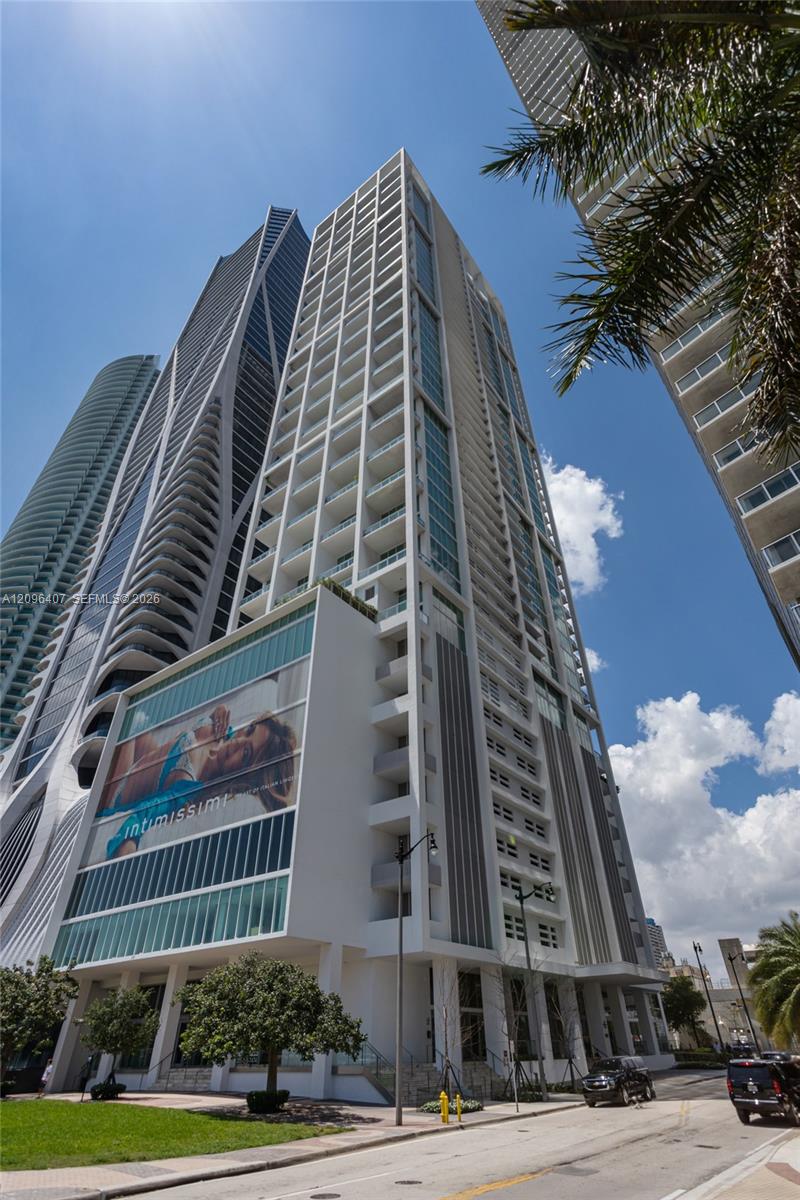 High-rise condominium at 1040 Biscayne Blvd, viewed from the street with neighboring towers and palm fronds.