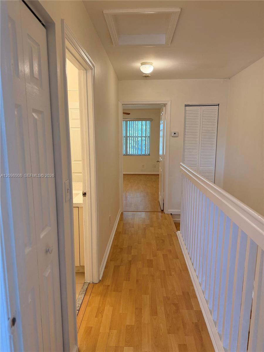 Upstairs hallway with hardwood floors, white stair railing, and louvered closet doors.