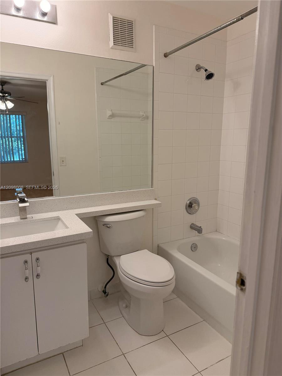 Bathroom with a white tub and tiled shower beside a toilet and vanity.
