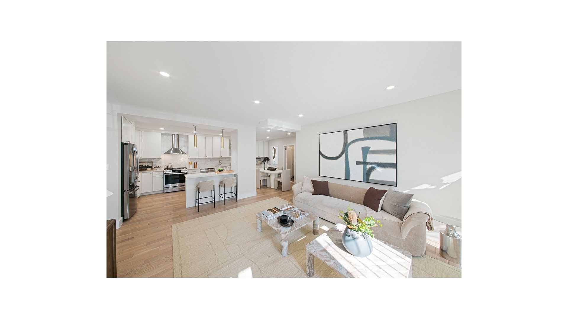 Open living room and kitchen with a light sofa, white cabinetry, and a breakfast counter.