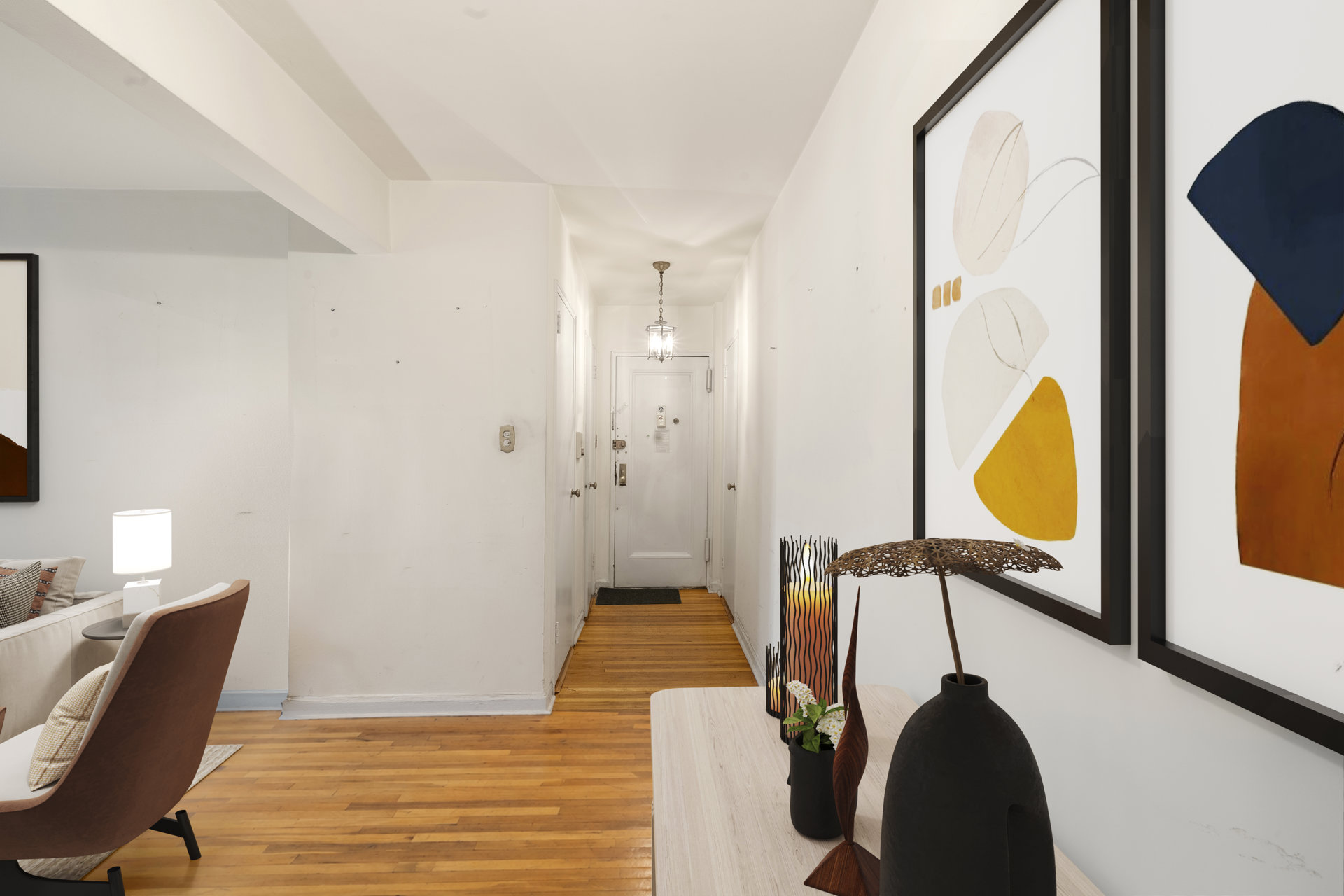 Apartment entry hall with hardwood floors, framed abstract art, and a view into the living area.