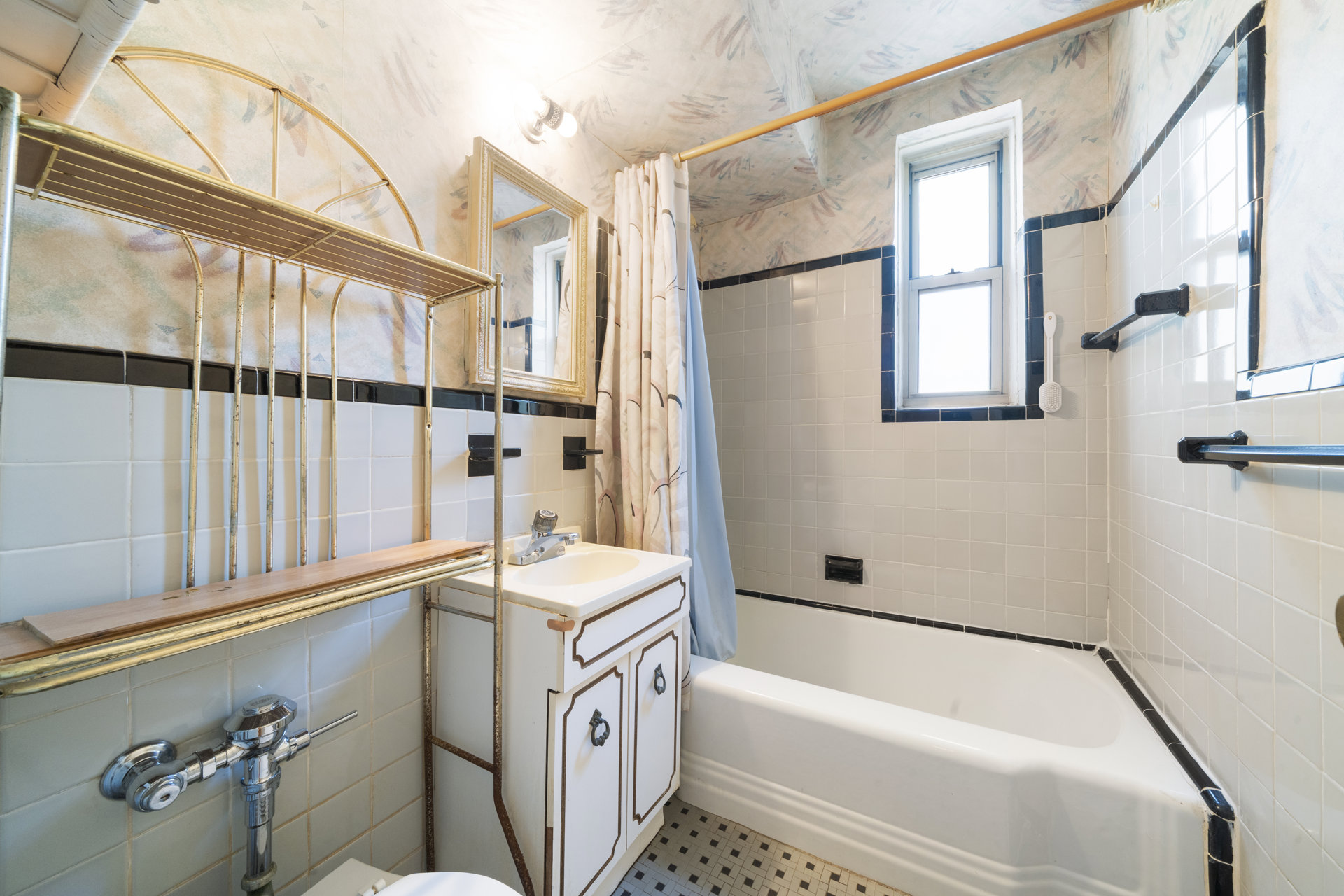 Bathroom with a bathtub, tiled walls, vintage brass shelving, and a window.