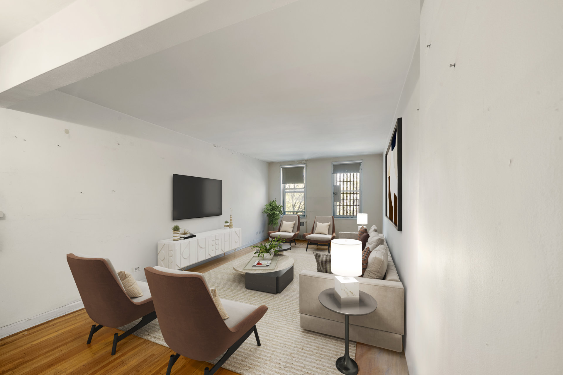 Staged living room with hardwood floors, a long sofa, and two large windows.