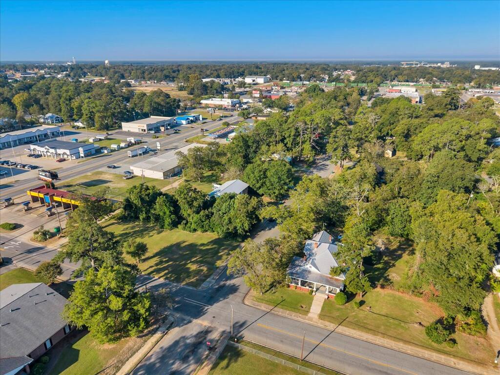 Aerial view of a house beside tree-lined streets and commercial buildings.