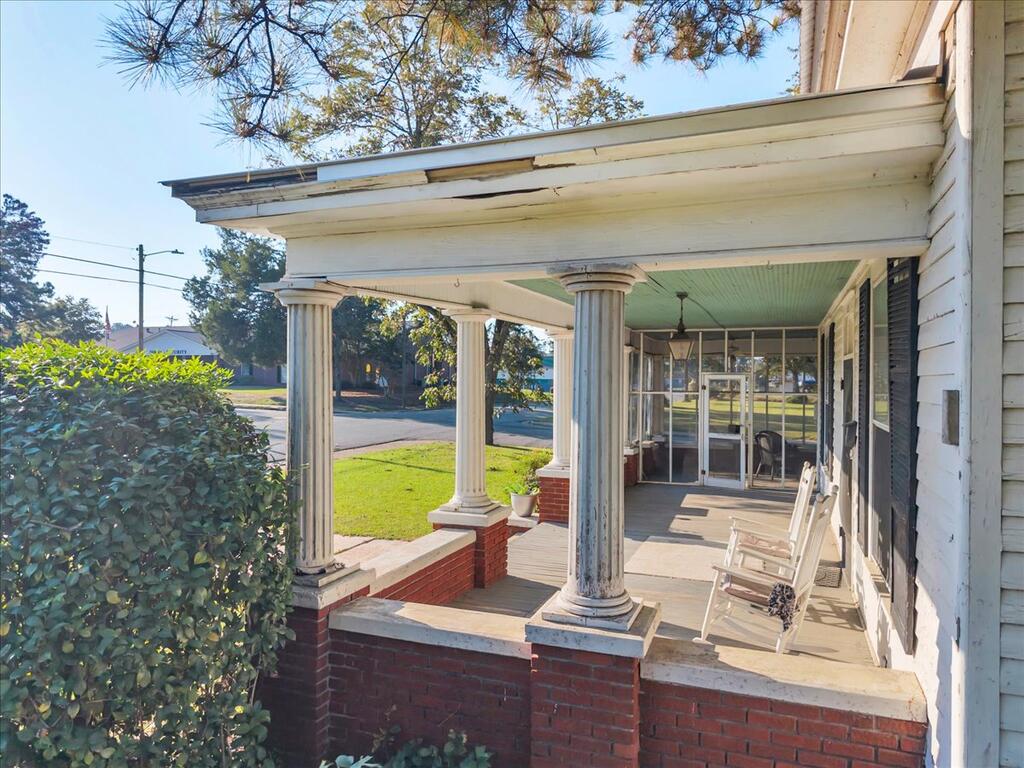 Covered front porch with white columns, brick bases, and rocking chairs.