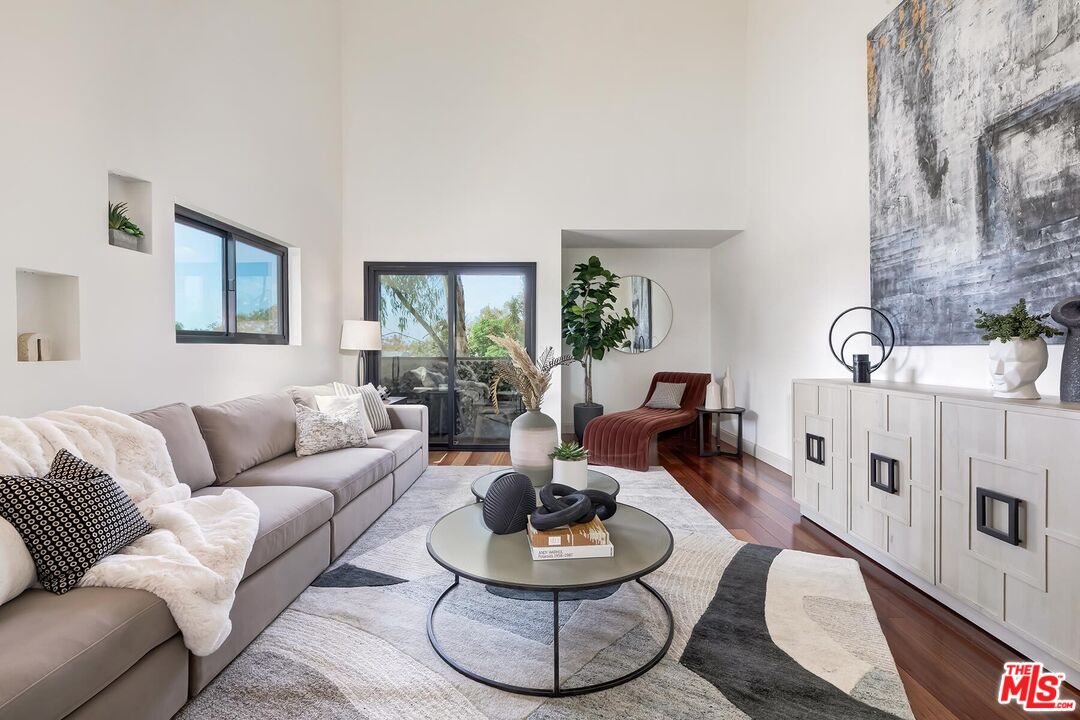 Furnished living room with a gray sectional, red chaise, and sliding doors to a balcony.
