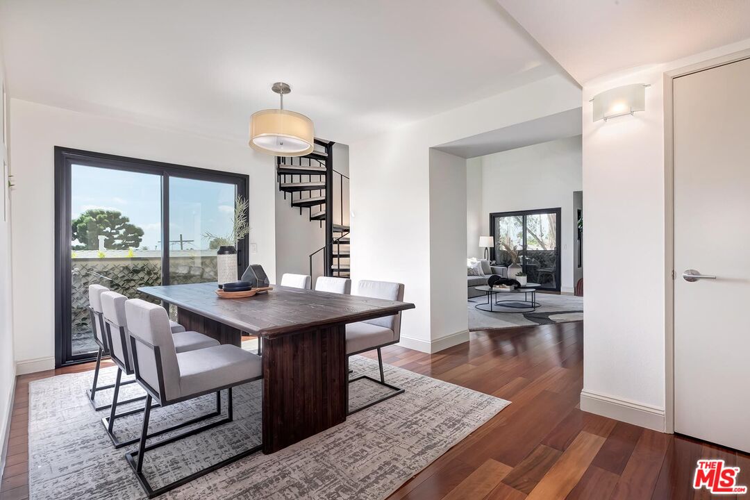 Dining room with a dark wood table, patio doors, and a spiral staircase.