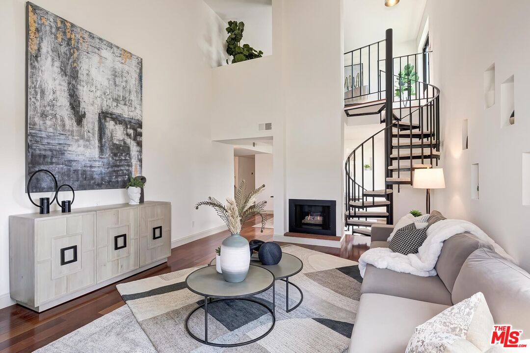 Living room with a black spiral staircase, fireplace, and large abstract painting.