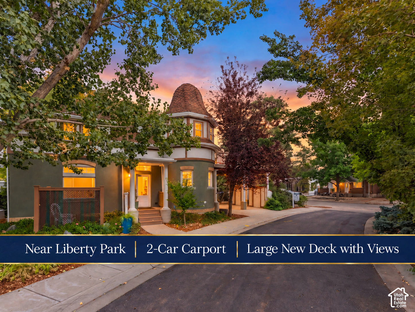 Two-story turreted home at dusk, framed by trees, with a banner noting its carport and deck.
