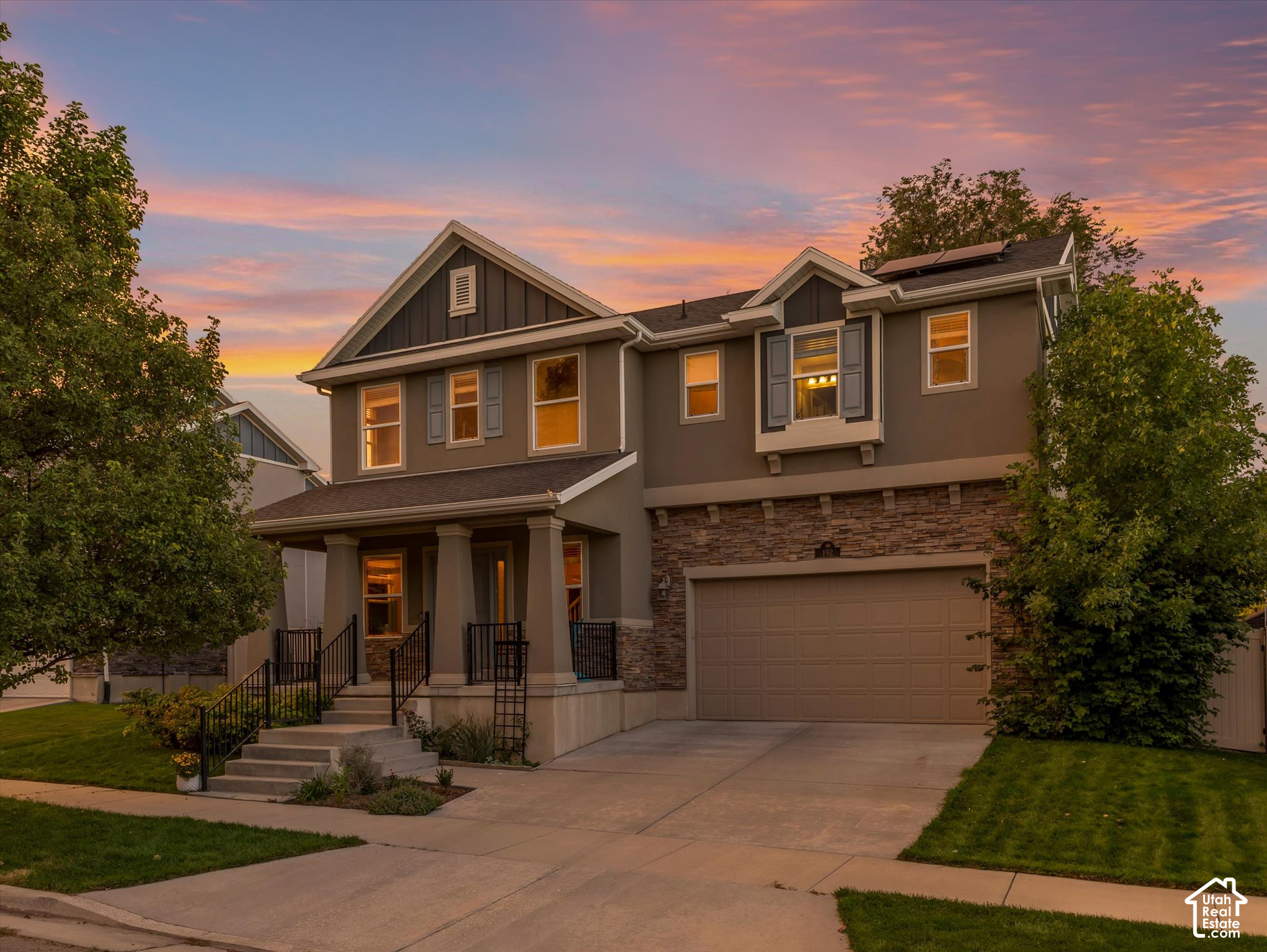 Two-story gray home with stone facade and attached garage at dusk.
