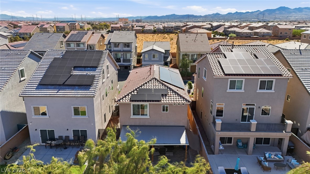 Rear view of homes with rooftop solar panels, patios, and mountains in the distance.