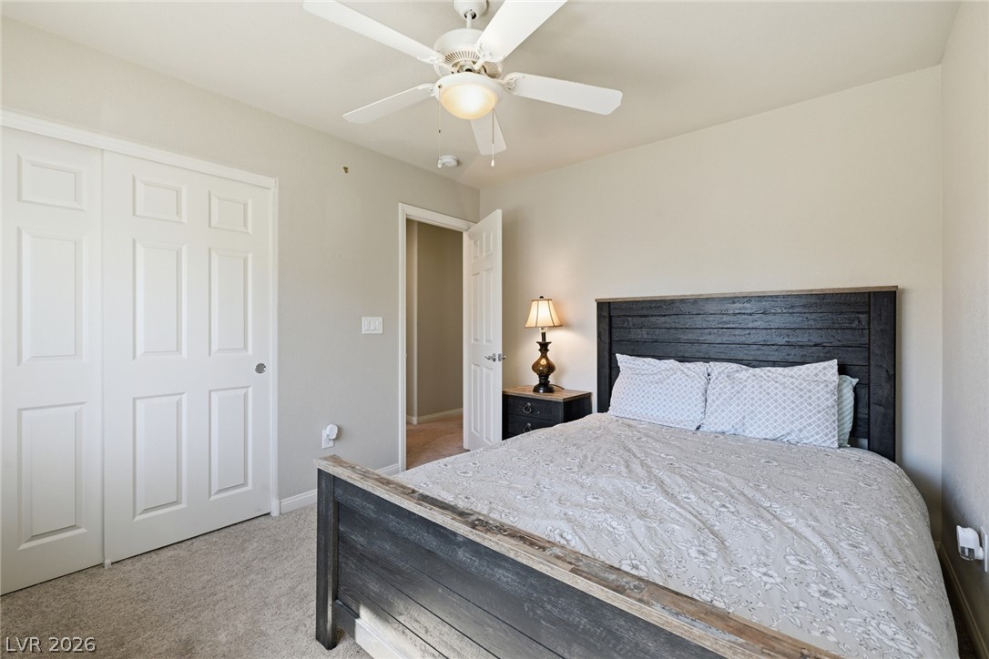 Bedroom with a dark wood bed, patterned bedding, sliding closet doors, and ceiling fan.
