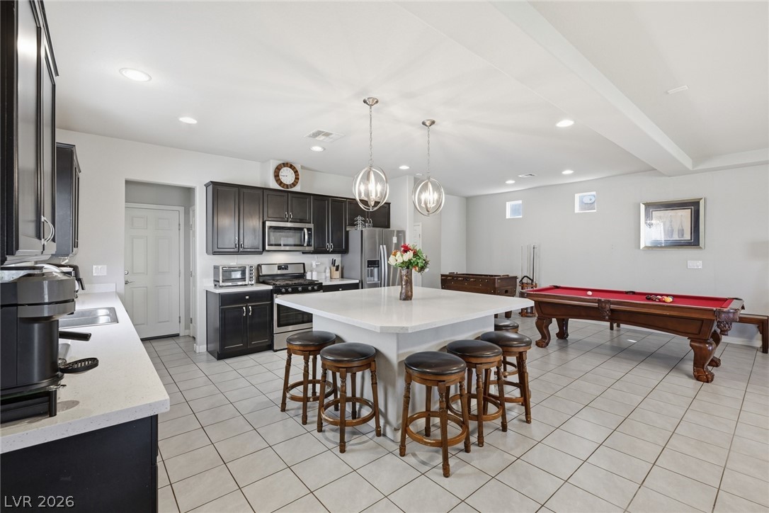 Kitchen and recreation area with a large island, dark cabinets, and a red-felt pool table.