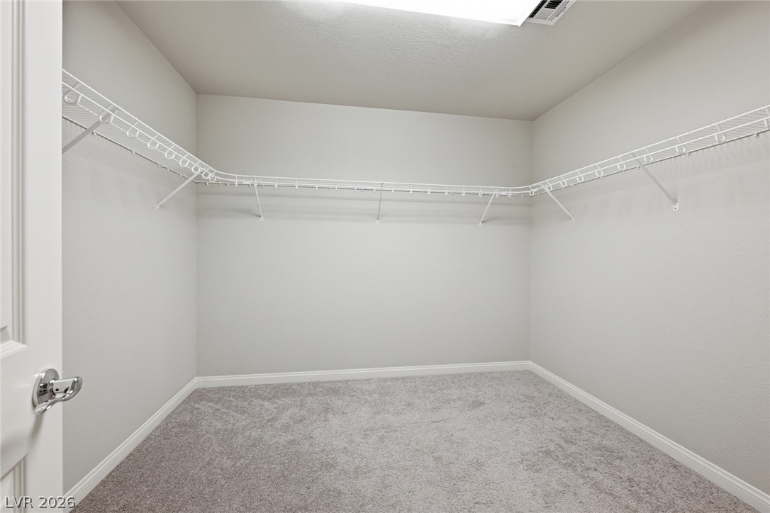 Empty walk-in closet with gray carpet and white wire shelving on three sides.
