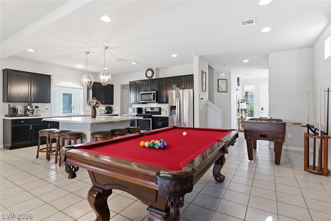 Game room with a red-felt pool table in front of a dark-cabinet kitchen.
