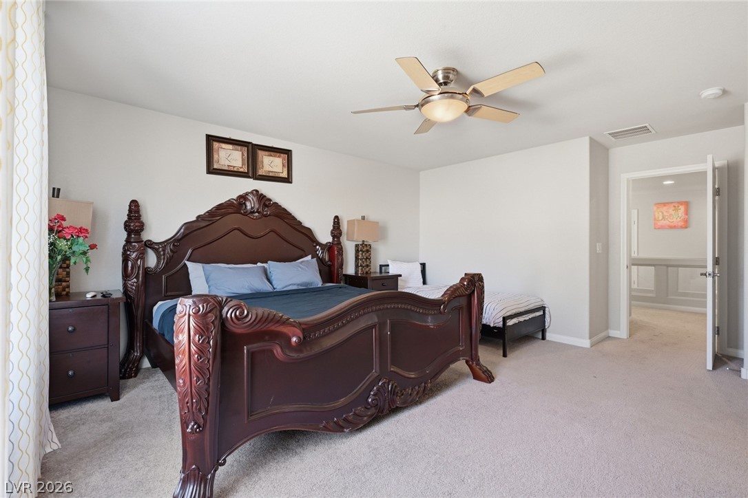 Furnished bedroom with an ornate dark wood bed, blue bedding, and a ceiling fan.