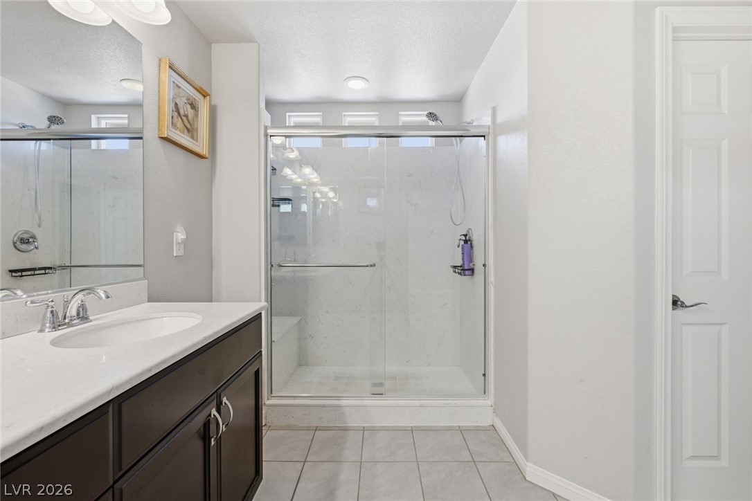Bathroom with dark wood vanity and a spacious glass-enclosed shower with a built-in bench.