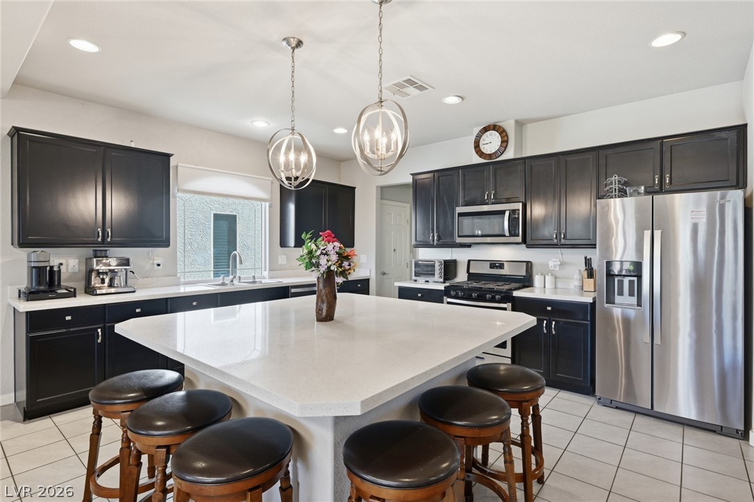 Kitchen with dark cabinets, stainless steel appliances, and a large white island surrounded by bar stools.